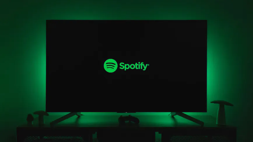 Headphones beside a smartphone displaying a music playlist