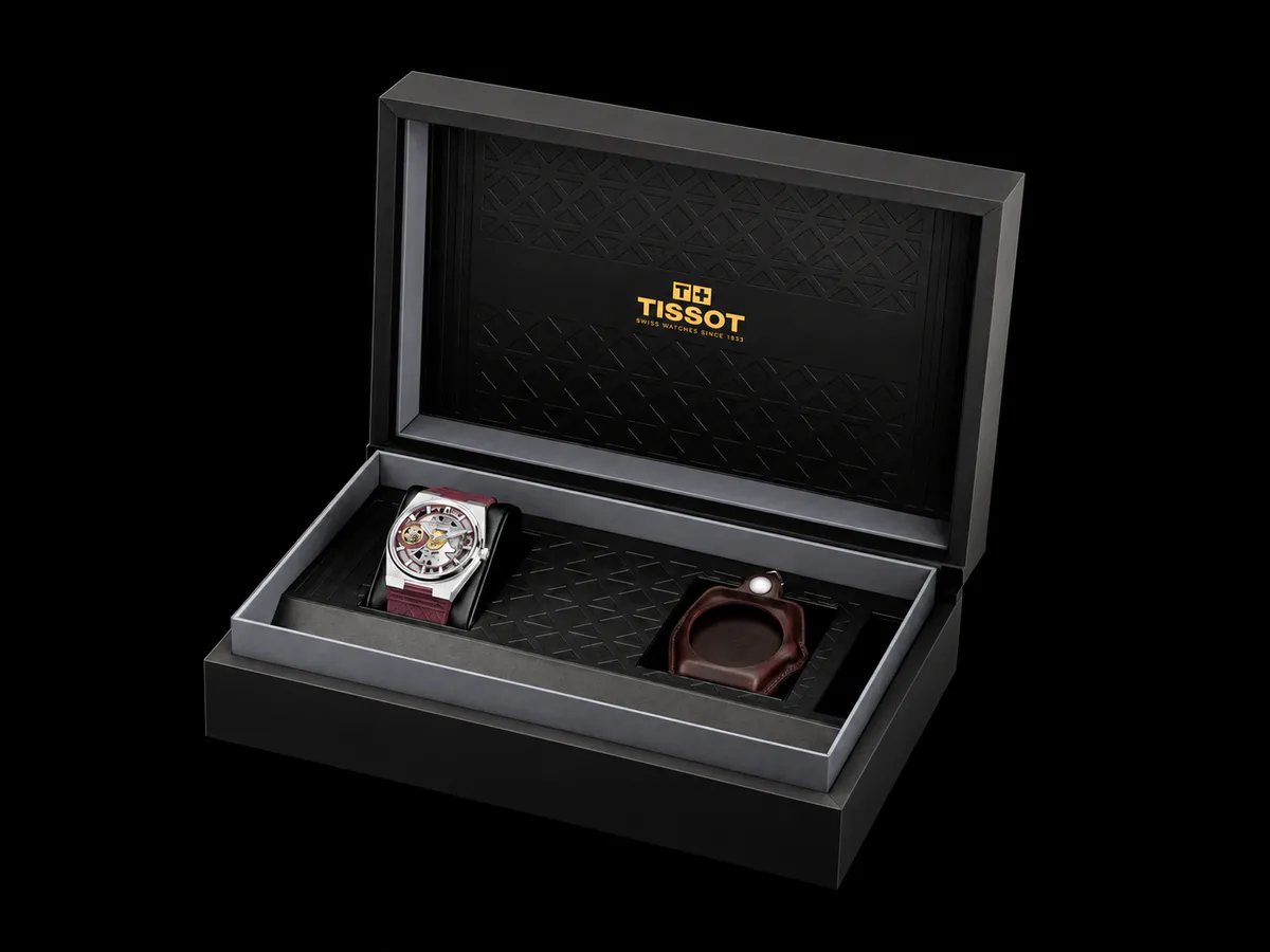 Mechanical wristwatch beside leather straps and a pocket-watch chain