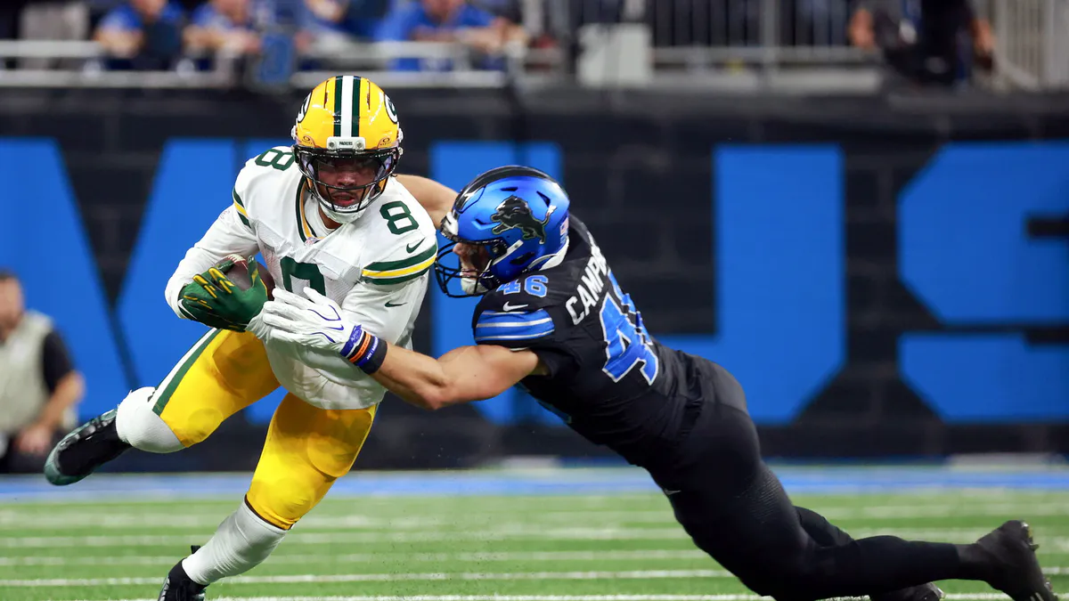 An American football on a field near a sideline