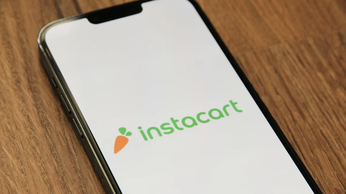 Grocery bags beside a smartphone displaying a delivery interface