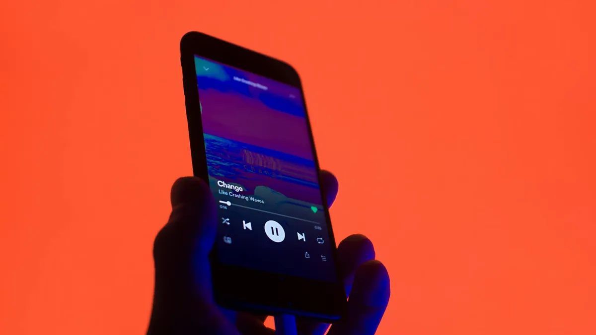 Headphones beside a smartphone displaying an audio waveform