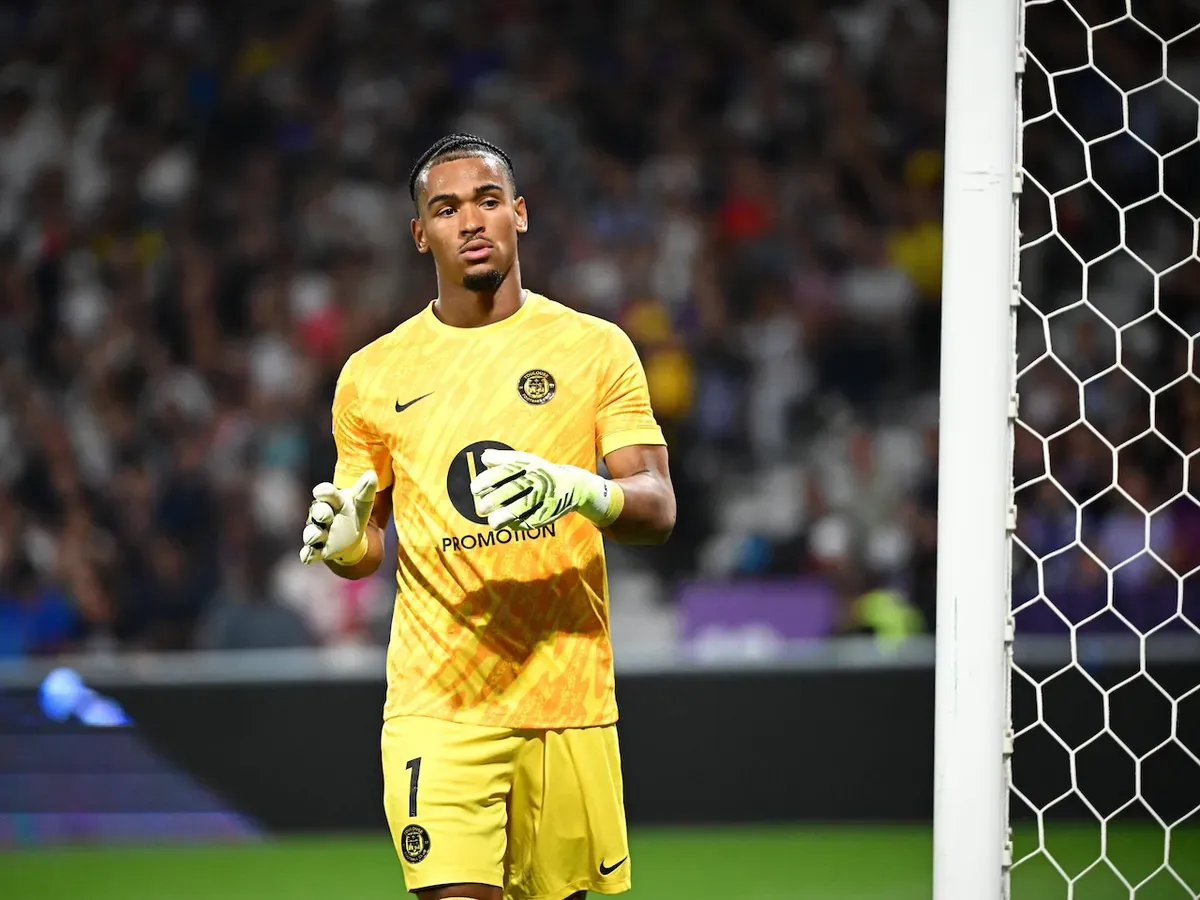 Goalkeeper gloves beside a football on a grass pitch